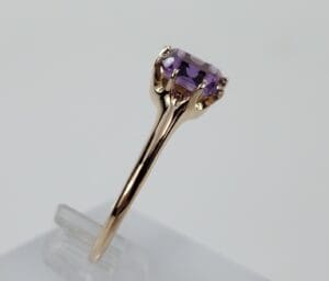 Gold ring with purple gemstone on display.