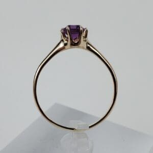 Gold ring with purple gemstone on display.