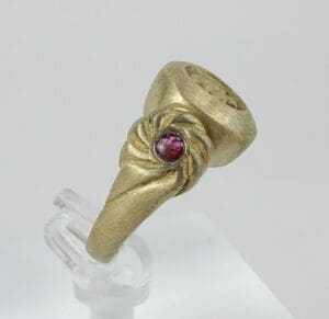 Gold ring with red gemstone detail.