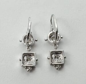 Silver square drop earrings on display.