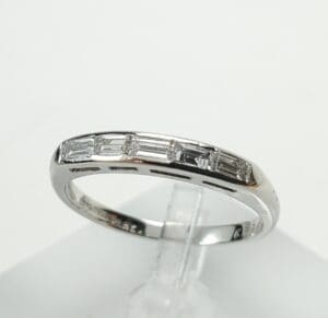 Silver ring with rectangular gemstones on display.
