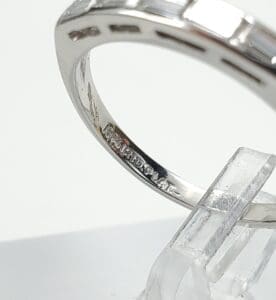 Silver ring with engraved markings on stand.