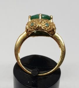 Gold ring with green gemstones on display.
