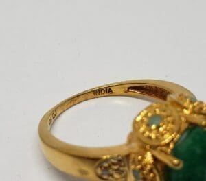 Gold ring with green gemstone and engraving.