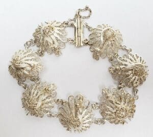 Ornate silver bracelet with intricate peacock designs.