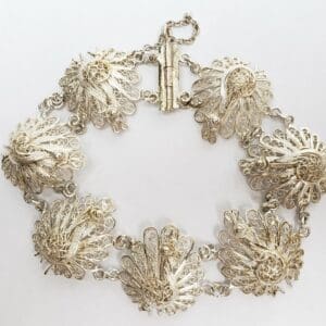Ornate silver bracelet with intricate peacock designs.