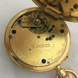 Gold pocket watch mechanism with engraved details.