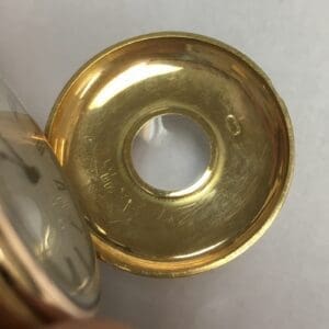 Gold pocket watch cover with circular opening.