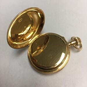 Open gold pocket watch on white surface.