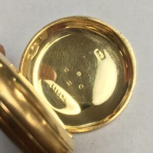 Open gold watch case showing engravings.