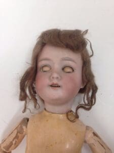 Antique doll with closed eyes and curly hair.