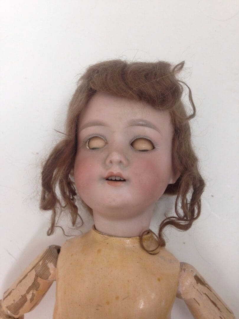 Antique doll with closed eyes and curly hair.