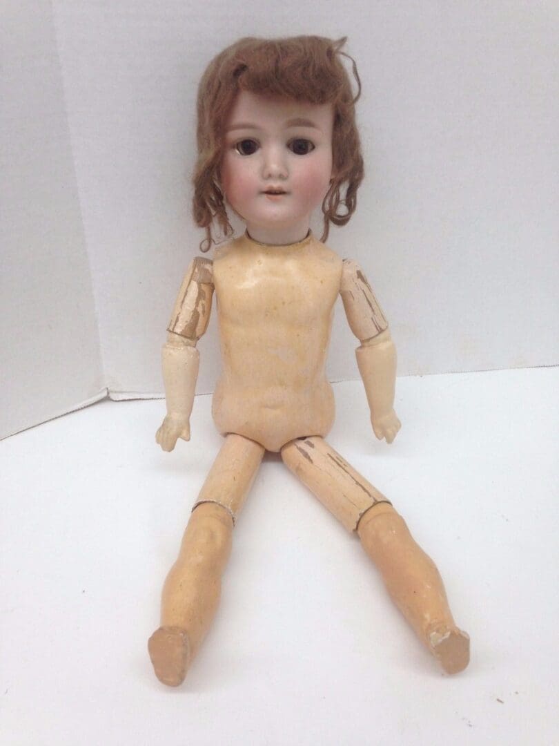 Antique doll with articulated limbs sitting.