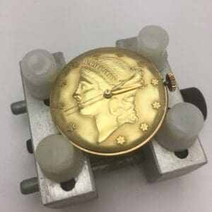 Gold watch face with engraved profile design.