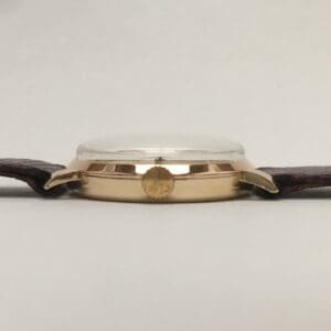 Gold wristwatch with brown leather strap.
