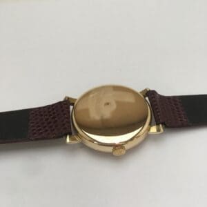 Gold watch with brown leather strap.