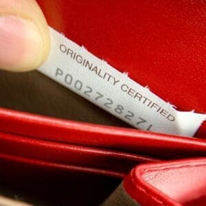 Red leather item with originality certified tag.