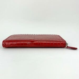 Red crocodile-pattern zipper wallet on display.