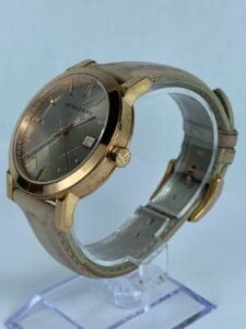 Gold watch with leather strap on display.