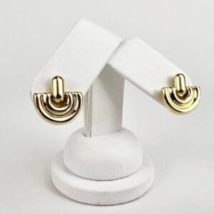 Gold earrings on white display stand.