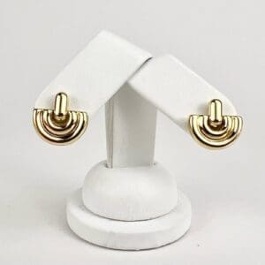 Gold earrings on white display stand.