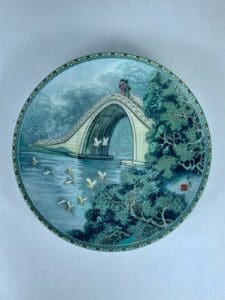 Decorative plate with bridge and birds design.