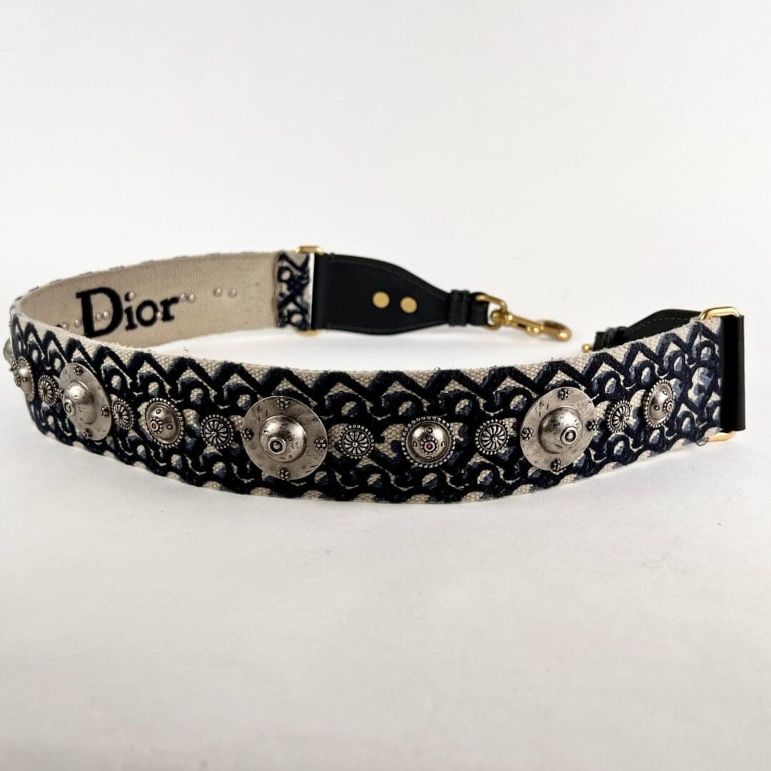 Embroidered Dior strap with decorative metal accents.