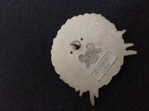 Disney pin back with logo and text.
