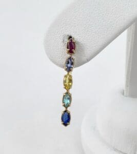 Colorful gemstone dangling earring on display stand.