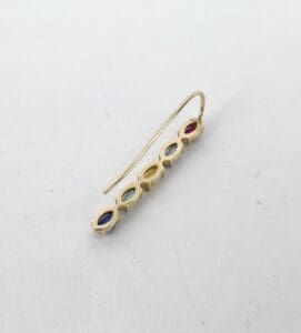 Gold earring with colorful gemstones on white.