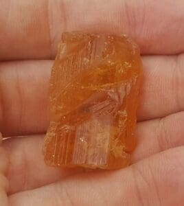 Orange crystal held in a person's hand.