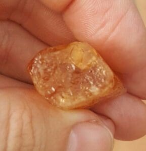 Hand holding a translucent amber stone.