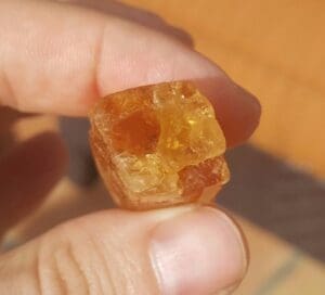 Hand holding a translucent orange mineral.