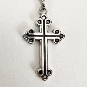 Silver cross pendant with ornate design.