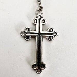 Silver cross pendant with ornate design.