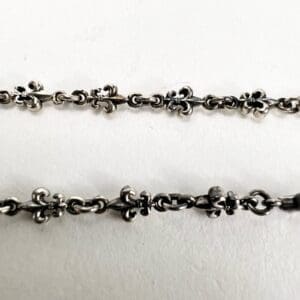 Silver chain with fleur-de-lis design.