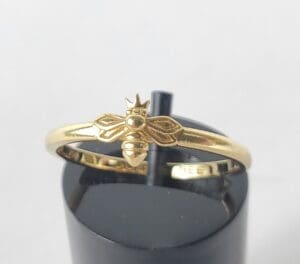 Gold ring with bee and crown design.