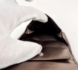 Empty brown wallet with gloved hand.