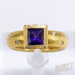 Gold ring with square purple gemstone.