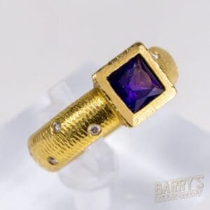 Gold ring with purple gemstone and diamonds.