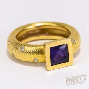 Gold ring with purple gemstone and diamonds.