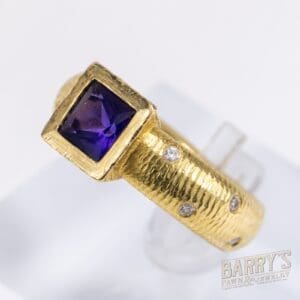 Gold ring with purple gemstone and diamonds.