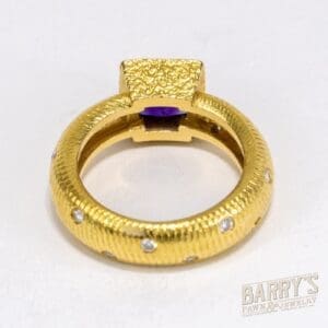 Gold ring with gemstones and purple stone.