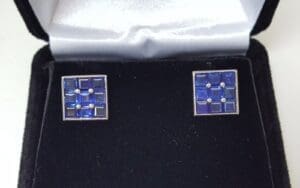 Square blue cufflinks in a black box.