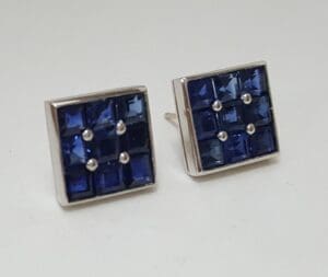 Square silver earrings with blue gemstones.
