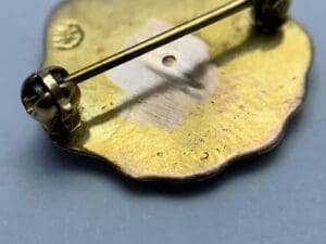 Gold pin with a scalloped shape back.