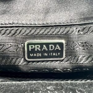 Prada label on black fabric background.
