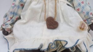 Doll wearing plaid dress with heart necklace.