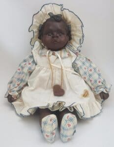 Vintage doll in bonnet and patterned dress.