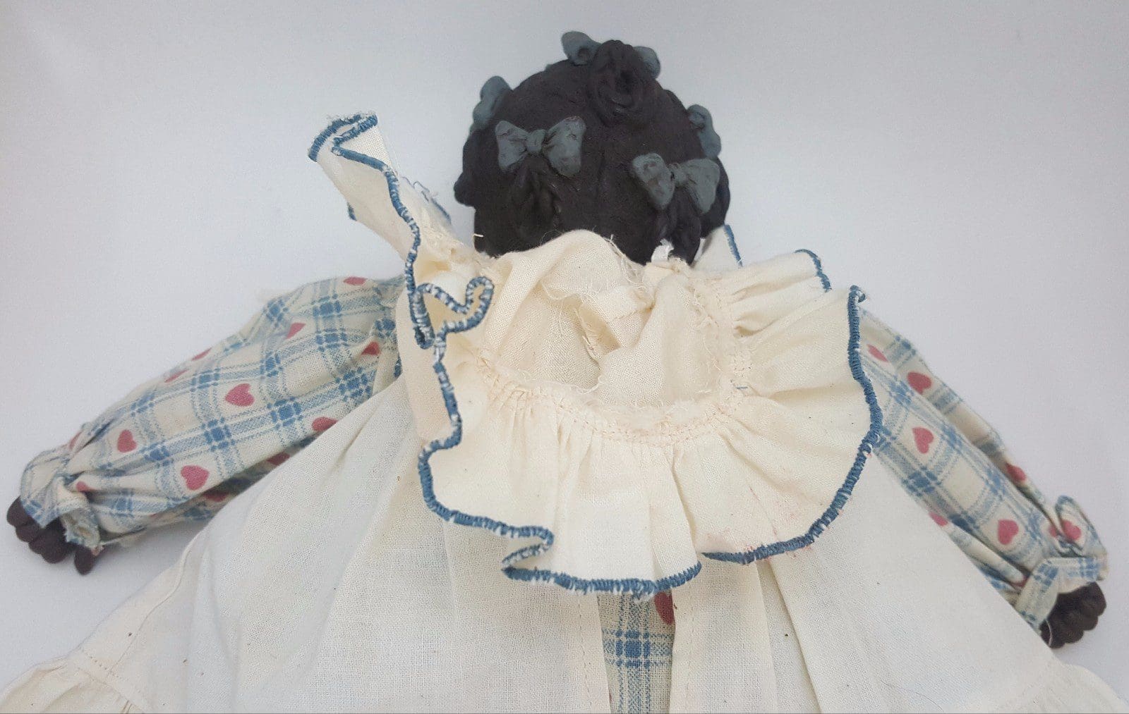 Back view of doll in checkered dress.